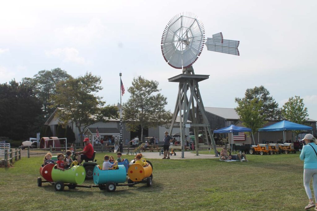 A windmill and children on a train ride at Hallockville Country Fair