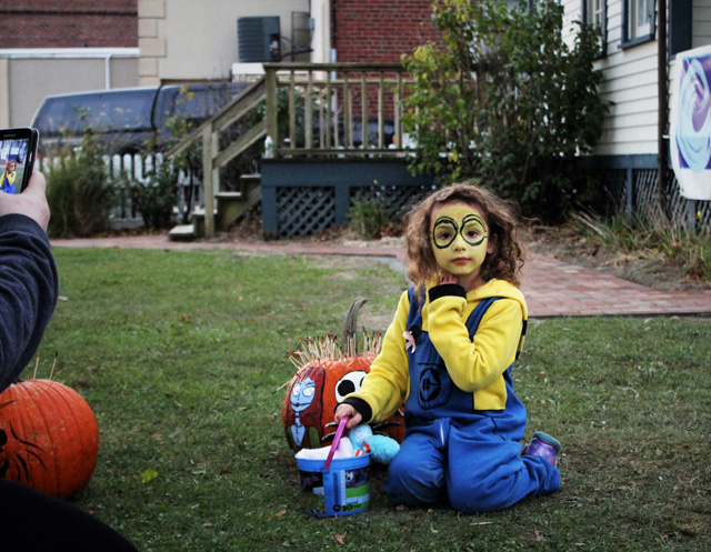 Harmony Orlowski (minion, Port Jefferson Station) posing for a photo with her mother Melissa Orlowski’s prize-winning pumpkin. Winners were decided by number of toothpicks inserted into the pumpkin by the public.   
