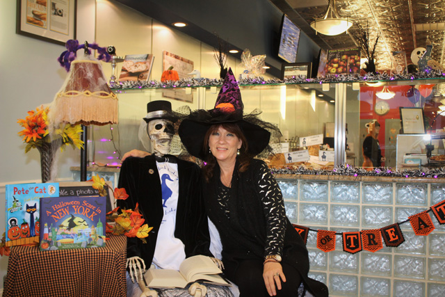 Nancy Kouris (owner of the Blue Duck Bakery Café) posing with the Blue Duck’s Halloween mascot, Odin (skeleton) – who is reading a collection of Edgar Allen Poe poems. This is Odin’s second Halloween at Blue Duck. He is named for the Norse god Odin, who is the god of war and poetry in Norse mythology.   