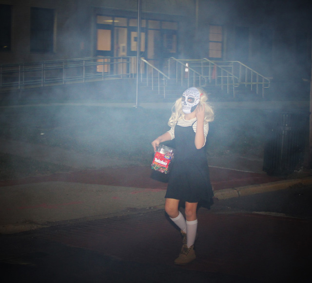 A sugar-skull masked girl walking down to Main St. to start the parade. 