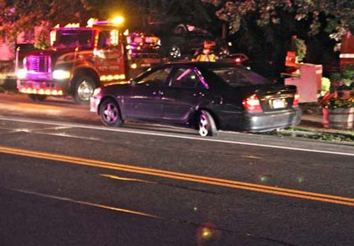 JENNIFER GUSTAVSON PHOTO | Oscar Aragon's Honda Civic gets transported from Main Road in Aquebogue Thursday night on a flatbed truck. The car he struck, owned by a St. James man, was towed from the scene.