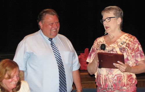TIM GANNON PHOTO  |  Riverhead School Board president Ann Cotten Degrasse hands a plaque to Joe Ogeka.