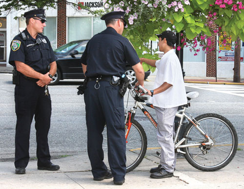 BARBARAELLEN KOCH FILE PHOTO | Riverhead police speaking to a Hispanic bicyclist on West Main Street in downtown Riverhead in 2009.