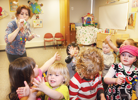 Children try to catch mini-bubbles blown by instructor Kathy Roeder of Patchogue during Preschool Playtime at Riverhead Free Library Friday afternoon. They also worked with Play-Doh, made necklaces, pretended to be frogs and sang a song about a boa constrictor. The program's last spring session takes place Friday.