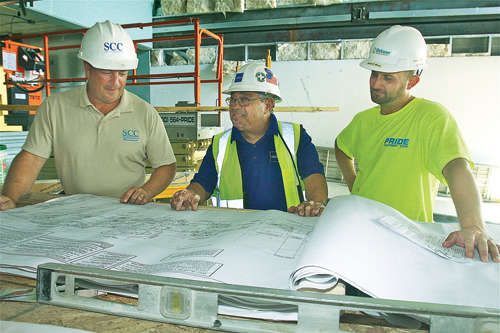 Keith DeLucia (from left), project manager with School Construction Consultants, Steve Uzzi, field supervisor for Stalco Construction in Islandia, and Sam Bailey, project manager for DeLuxe Building Systems of Pennsylvania, go over plans at the charter school. (Credit: Barbaraellen Koch)
