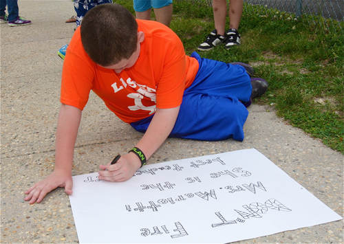 Timmy Duffy, 12, writes a message on oak tag defending his brother's teacher, Jutta Marrioti. 