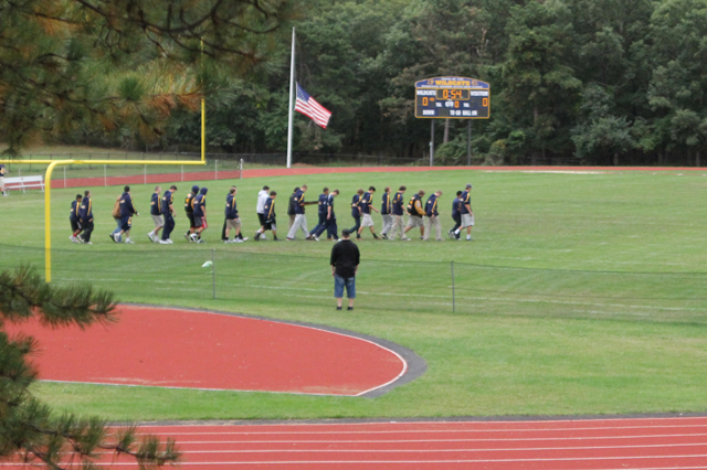 Members of the Shoreham-Wading River football team walk out onto the field during last Thursday's vigil. (Credit: Jen Nuzzo)