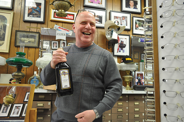 Allied Optical Plan owner Jerry Steiner shows a customer a bottle of Manischewitz wine he received as a gift for passover. (Credit: Grant Parpan)