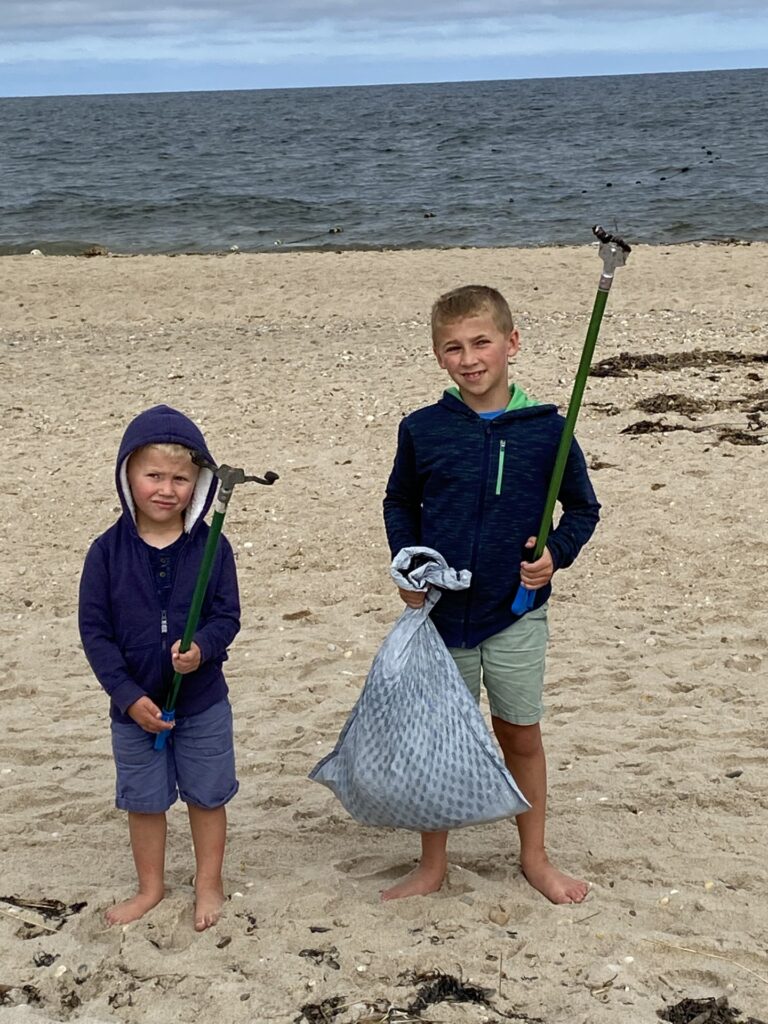 Two boys hold full garbage bags after a beach cleanup.