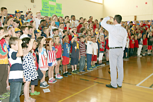 Riley Avenue second-graders, under the direction of music teacher Keith Maguire, sang patriotic songs Friday in salute to the American flag. (Credit: Sandra Kolbo/Riverhead School District)