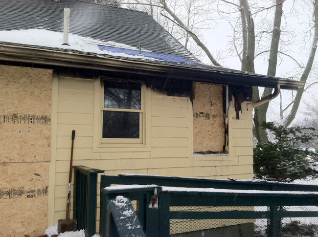 The damaged home was boarded up in spots Friday morning. (Credit: Michael White)
