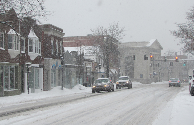 Cars make their way trough a snowy downtown Riverhead Thursday afternoon. (Credit: Tim Gannon)