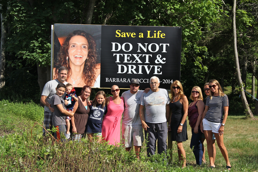 Members of the Tocci family in font of the sign Friday afternoon. (Credit: Carrie Miller)