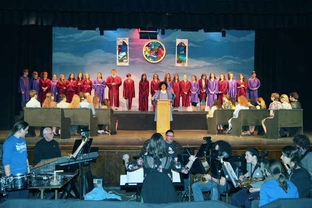 Jesse Goodale as the Reverend Moore with the choir in the background and the pit orchestra in the foreground. (Credit: Riverhead schools)