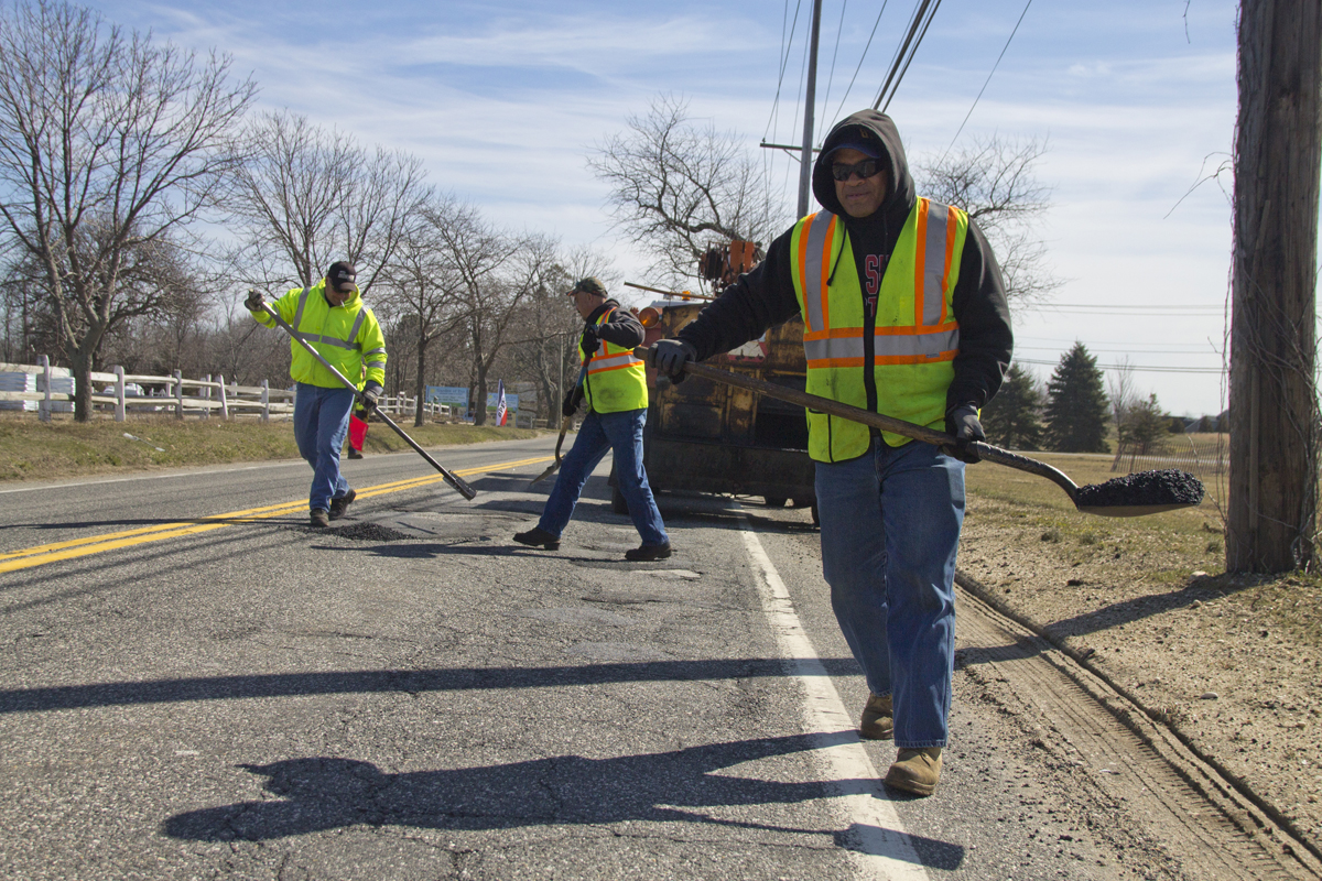 A Riverhead highway crew begins patching up potholes along Sound Avenue Wednesday morning. The workers said this year is the worst they can remember. (Credit: Paul Squire)
