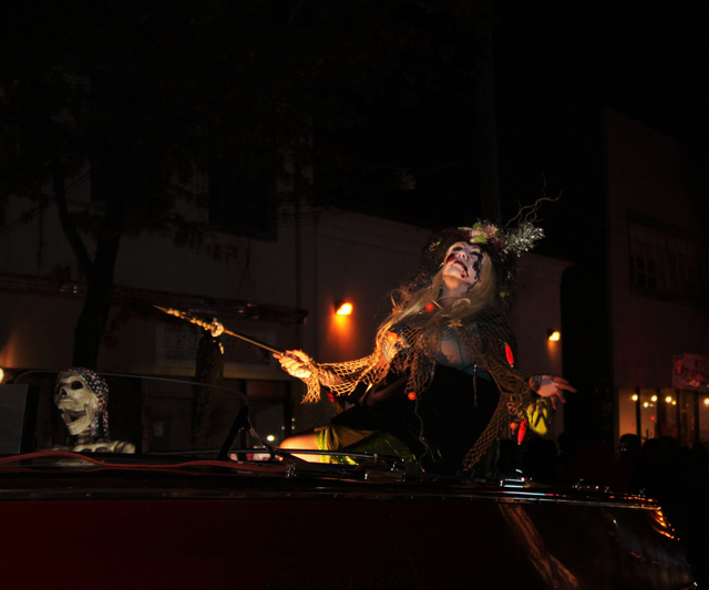 Zombie mermaid being towed in a motorboat with her skeleton passenger.