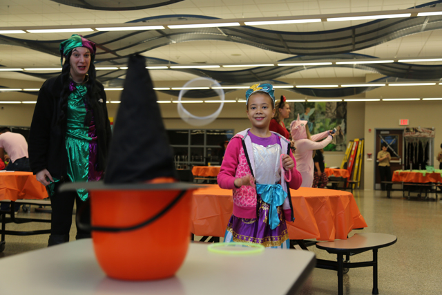 Trinity Strand, 7, tosses a ring at the witch's hat in the Riverhead High School spookified cafeteria at Safe Halloween.