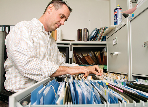 Code enforcement officer Richard Downs goes through some of the files stored in metal cabinets inside the department's office. (Credit: Paul Squire)