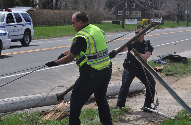 Police work to remove a utility pole from Main Road in Aquebogue after it was struck by a distracted driver. (Credit: Grant Parpan)