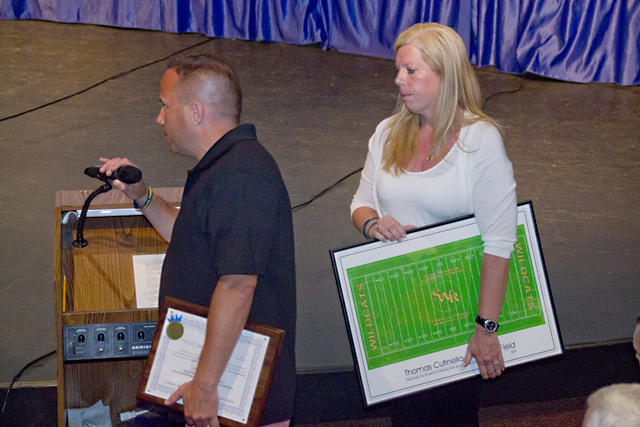 Frank and Kelli Cutinella accept a lithograph of the design featuring Thomas' name painted into the field around its center. (Credit: Paul Squire)