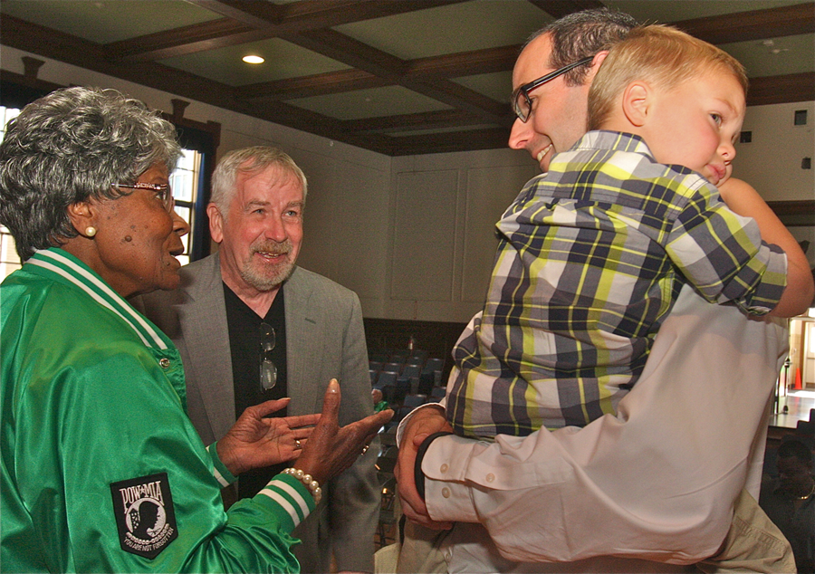 Mary Langhorn speaks with artist Gerald Slater of Littelton and Erik Eve of Patchogue, shown holding his son Benjamin Rodney Garfield Eve. Mr. Eve's father, Rodney, was standing next to Garfield Langhorn when he threw himself on the hand grenade that saved the lives of Mr. Eve and others.