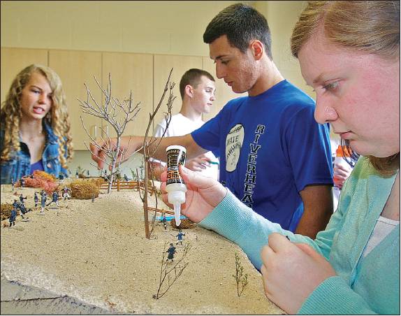 Riverhead High School student Emily Green (right) glues figurines last month on a diorama depicting a battle from the War of 1812. She and Megan Carrick (from left), John Vega, and Brian Brenton were students in Justin Cobis' history class. (Credit: Barbaraellen Koch)