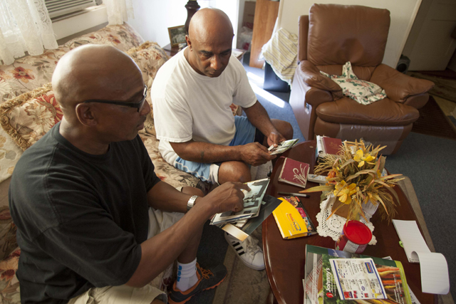 Malcolm (left) and Kevin Grigg look over pictures of their stepfather Monday. (Credit: Chris Lisinksi)