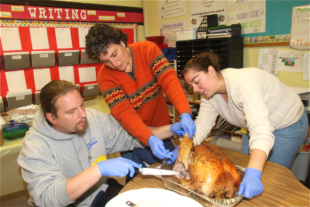 Parents Alfred and Karma Marshall help Georgette Zenk (center) carve up the 25 pound turkey at Roanoke Elementary. (Credit: Barbaraellen Koch)