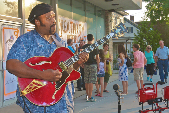 Guitarist Ahmad Ali of Islip performs on the street in front of the former Sears building. (Credit: Barbaraellen Koch)
