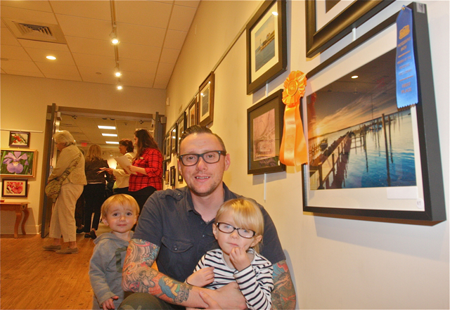 Jon Schusteritsch of Cutchogue posed with his children Max, 1 1/2, and Zoey, 4, by his photo chosen as the Friends Choice award for a landscape scene of docks and the bay at sunrise in New Suffolk. (Credit: Barbaraellen Koch) 