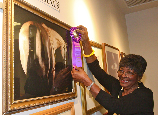 Friends of the Library Photo Show chairwoman Thelma Booker places the 'Best of Show' ribbon on Meghann Belser's portrait of a horse. (Credit: Barbaraellen Koch)