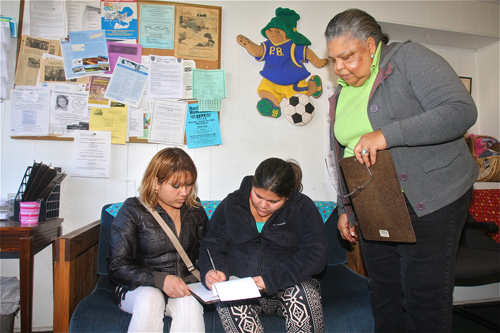 Sisters Yamileth and Maritza Carbajal, of Westhampton and Central Islip respectively, fill out paperwork for their monthly food allowance Friday afternoon as Long Island Council of Churches food pantry manager Carolyn Gumbs looks on. (Credit: Barbaraellen Koch photos)