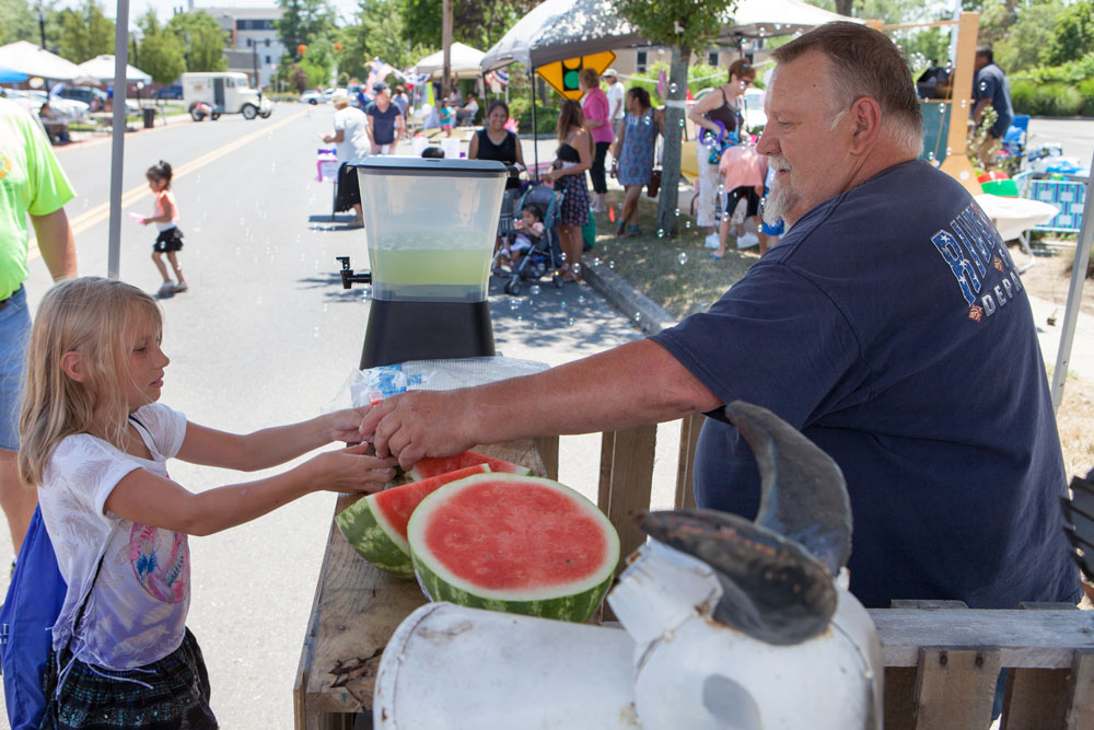 Peyton LaCombe, 9, of Riverhead accepts a slice of watermelon from Riverhead firefighter Joe Berezny. (Credit: Katharine Schroeder)
