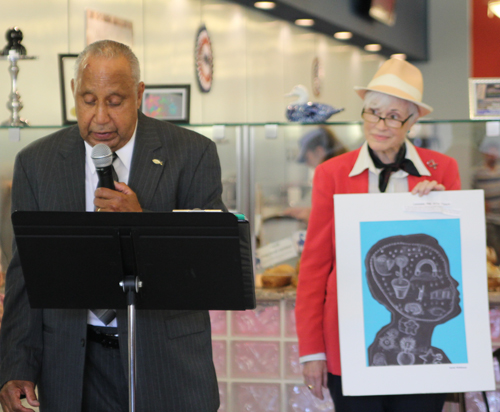 LeRoy Heyliger, grandfather of Mattituck Junior High student Justin McKinney, reads his grandson's poem "I am" as the event's organizer, Susan Dingle, holds Justin's artwork.