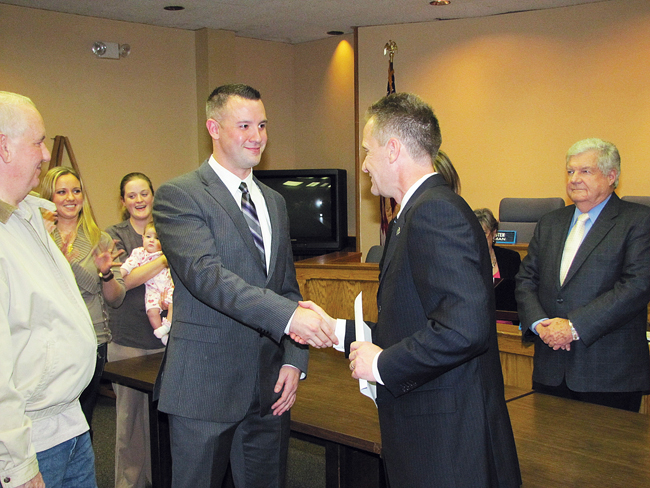Riverhead police officer Chris Burns is congratulated by Supervisor Sean Walter. (Credit: Tim Gannon)