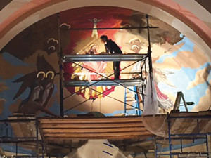 An artist works to repaint the main mural at St. Isidore. (Credit: Courtesy, Robert Kuznik)