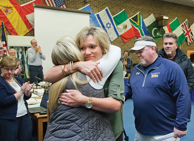 Kelli Cutinella (left), the mother of Shoreham-Wading River student Tom Cutinella, who died last year playing football, hugs Wildcat Athletics Club board member Regina McGee at a school board meeting Tuesady night. The booster club had just presented Ms. Cutinella with a $106,000 check to help start a foundation and scholarships in Tom's memory. (Credit: Paul Squire)