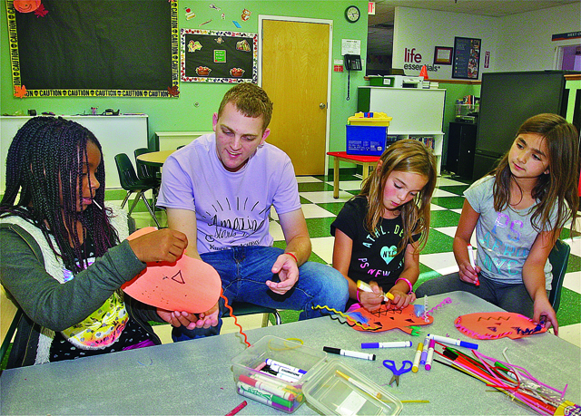 BARBARAELLEN KOCH PHOTOAnthony Mammina with students in after school care (from left) Eunique Trent, 10, Sophia Romeo,9, and Ava Cravotta, 9,  making decorations for the bulletin board at Kiddie Academy in Wading River Tuesday afternoon.