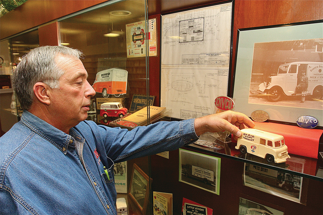 John Rienzo setting up his Divco memorabilia in the display case at Riverhead Free Library, where it is on view during October. (Credit: Barbaraellen Koch)