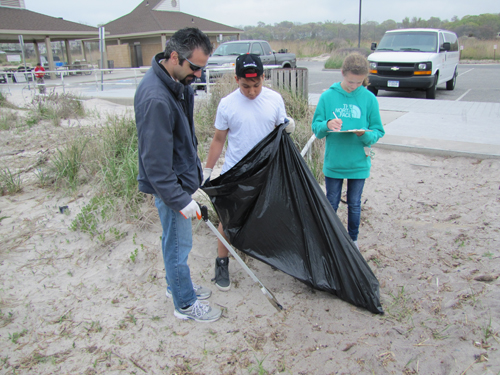 Konstantine Rountos and Celestino Pascual pick up trash while another student logs the type of trash.