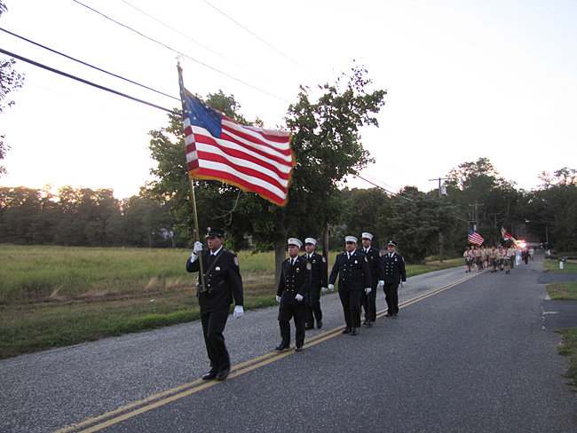 The Riverhead Fire Department marches down Park Road, with Wading River scouts behind them, at the Reeves Park memorial. (Credit: Tim Gannon)