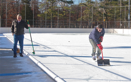 Councilman George Gabrielsen and hockey skater Justin Macdonald clearing the ice of some light snow that fell 2 days ago. (Credit: Barbaraellen Koch)