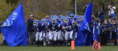 The Riverhead Blue Waves charge onto Coach Mike McKillop Memorial Field for their homecoming game against Bellport on Saturday. (Credit: Robert O'Rourk)