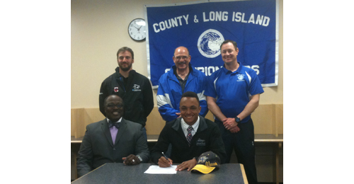 Riverhead sprinter Jacob Robinson, seated next to family friend Patrick Harris, signed to accept a scholarship from Merrimack College (Mass.). Standing, from left, are Riverhead assistant coach Will Razzano and the school's indoor and outdoor coaches, Sal Loverde and Steve Gevinski. (Credit: Bob Liepa)