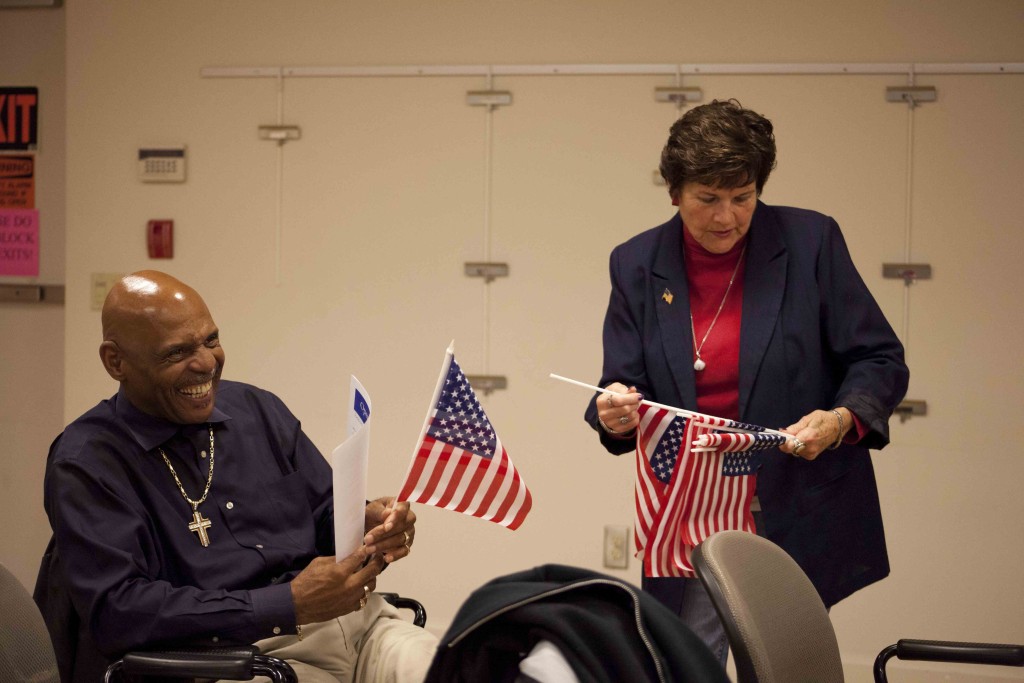 Ann Tessitor (right), a clerk with the library's senior services department, gives a flag to veteran Wilkens Young. (Credit: Chris Lisinski)