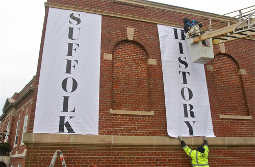 Ryan Egan (top) and Stephen Tang hang the vinyl tarps at Suffolk County Historical Society on Tuesday. (Credit: Barbaraellen Koch)