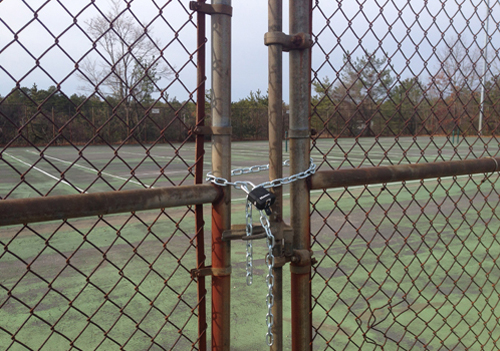 The Shoreham-Wading River High School tennis courts have been closed and locked since March after they were declared unsafe. Fixing them up will cost over $800,000. (Credit: Joe Werkmeister)