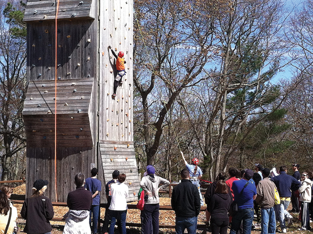 NYIT Vocational Independence Program students watch as their dean, Ernst VanBergeijk, scales a rock wall at the Baiting Hollow Scout Camp Friday. (Credit: Michael White)