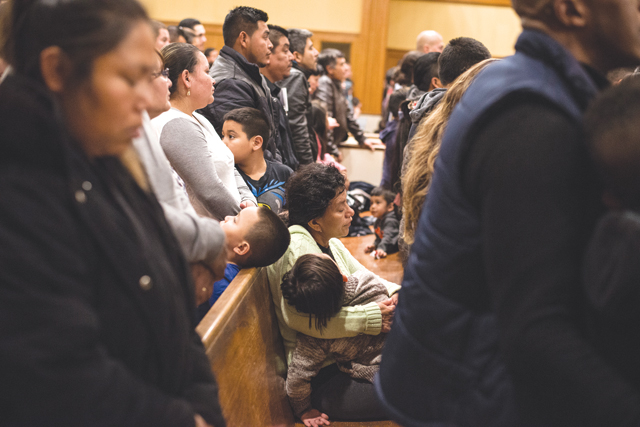 A woman holds a child during Sunday night Spanish language Mass at St. John the Evangelist Church in Riverhead the weekend after the election. It was a trying time for our local immigrant Hispanic community and I believe this image of the packed church captured both uncertainty and faith.  (Credit: Kevin Urgiles)