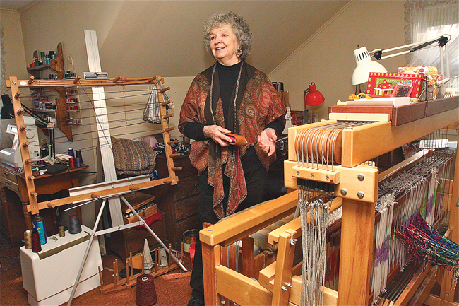 Natural fibers artist Barbara Ringewald of Cutchogue, wearing a shawl she made, demonstrates how she sets up the loom in her home studio before starting work on a new piece. (Credit: Barbaraellen Koch)